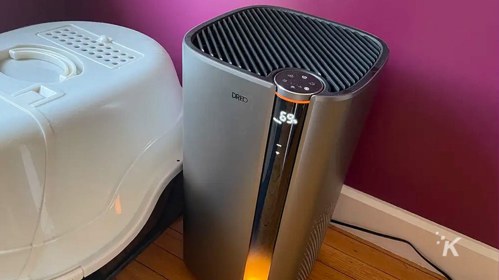 A modern home appliance stands in the middle of an indoor room, emitting a soft glow.