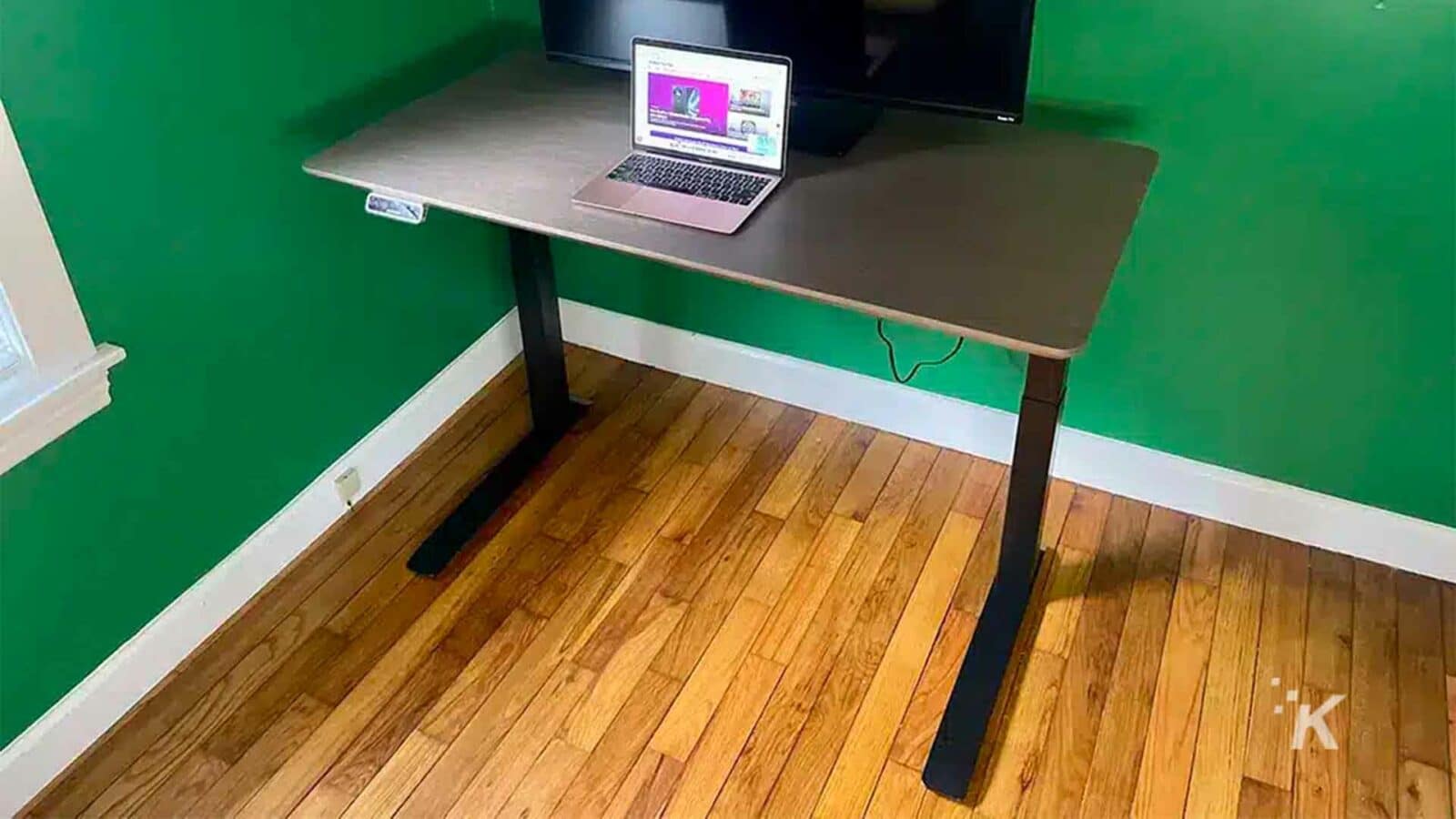 The laptop sits on the table.Flexisport E7 Premium standing desk