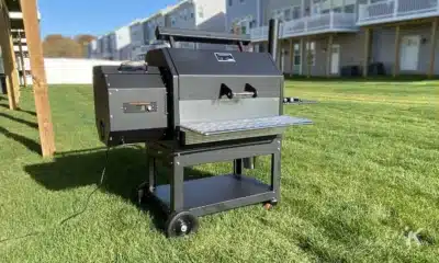 A pellet grill barbeque on a back lawn with houses in the distance