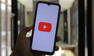 Person holding a phone with the YouTube logo on the screen.