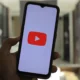 Person holding a phone with the YouTube logo on the screen.